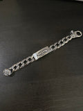 Metal charm bracelet with linked chain and fleur-de-lis accents