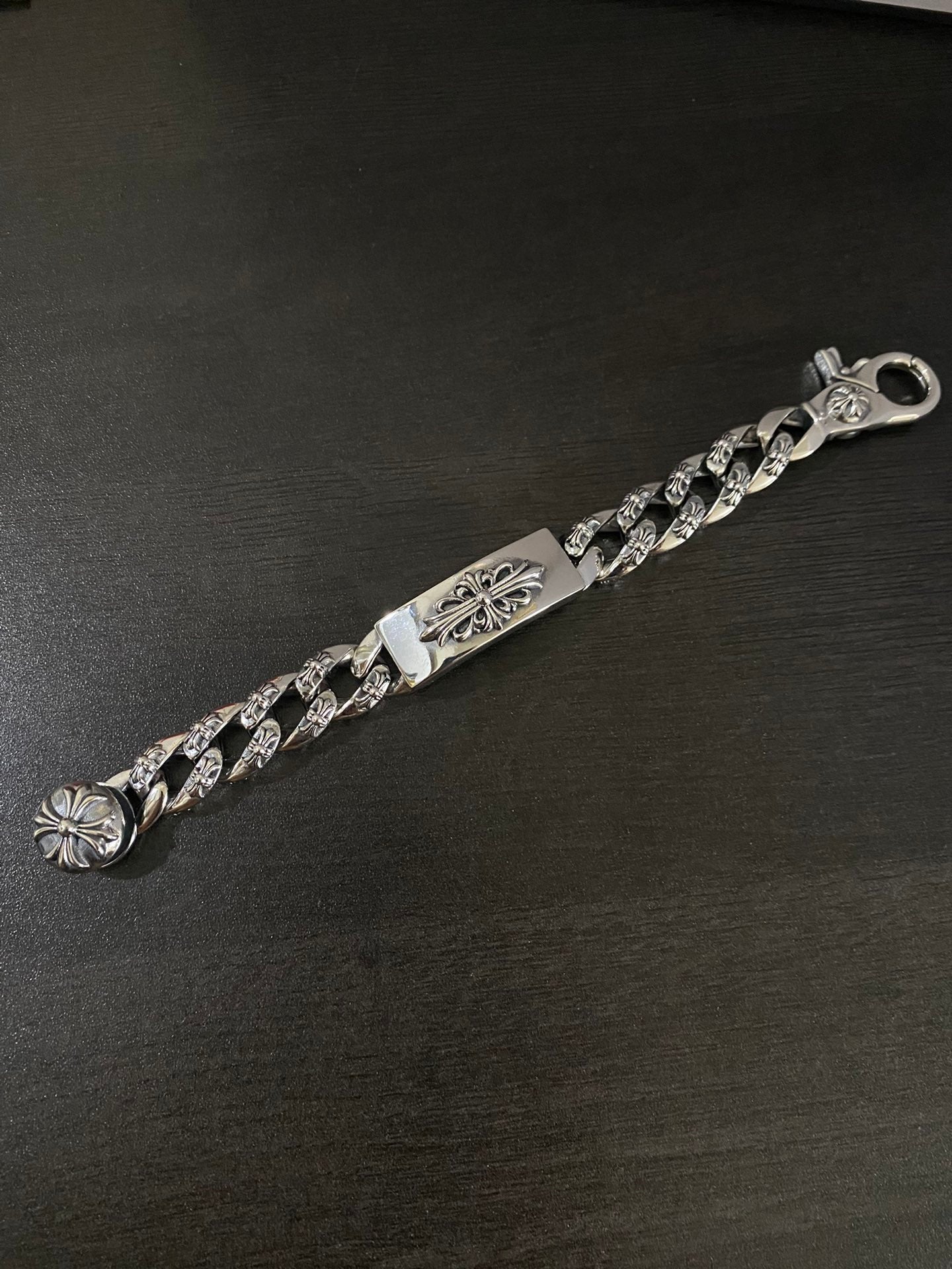 Metal charm bracelet with linked chain and fleur-de-lis accents