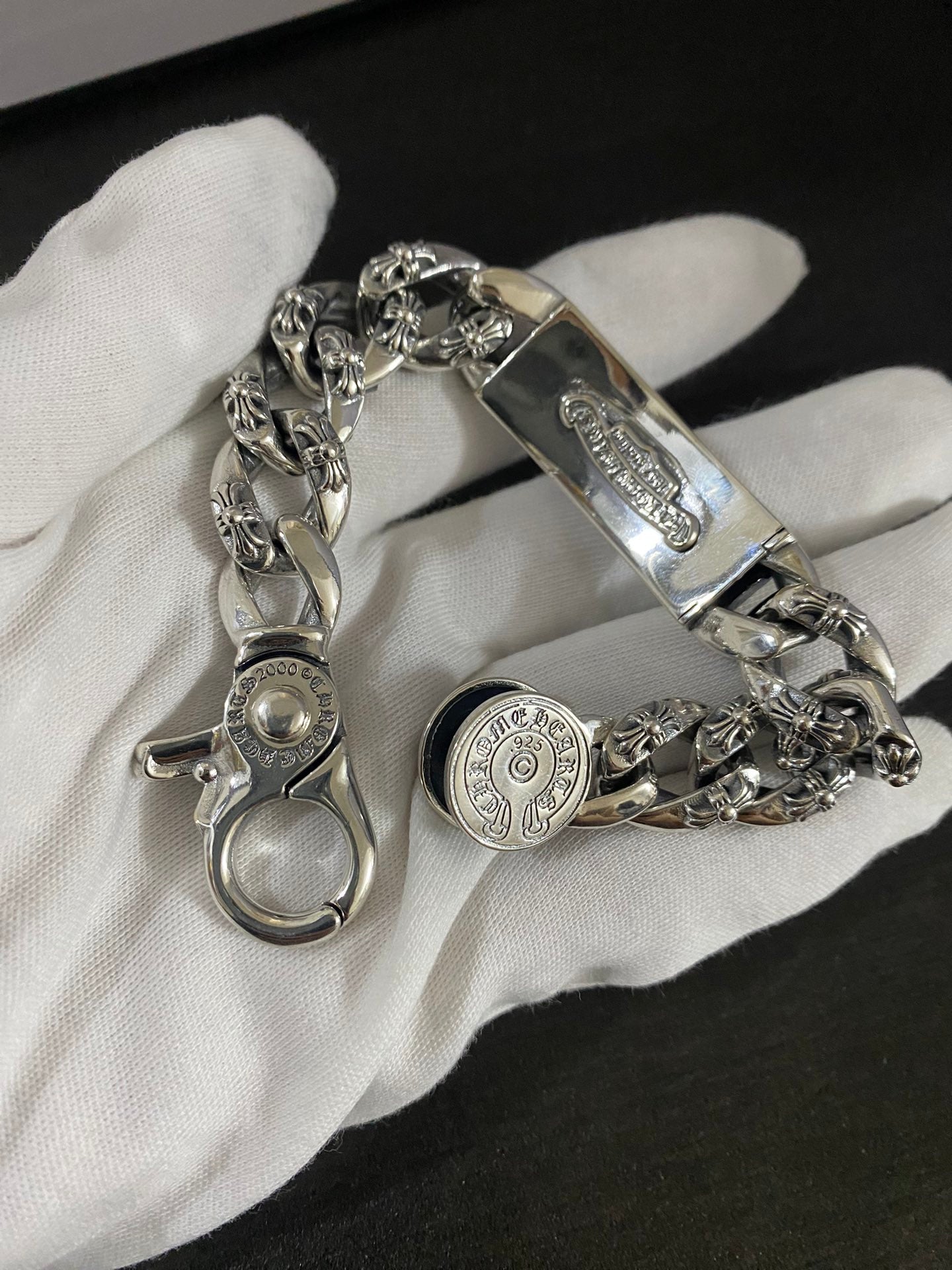 Chrome accessories charm bracelet with oval clasp and engraved links on white glove