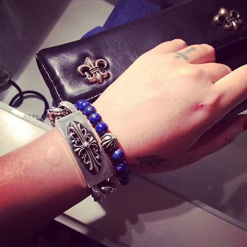 Leather and bead charm bracelet with fleur-de-lis charms on wrist