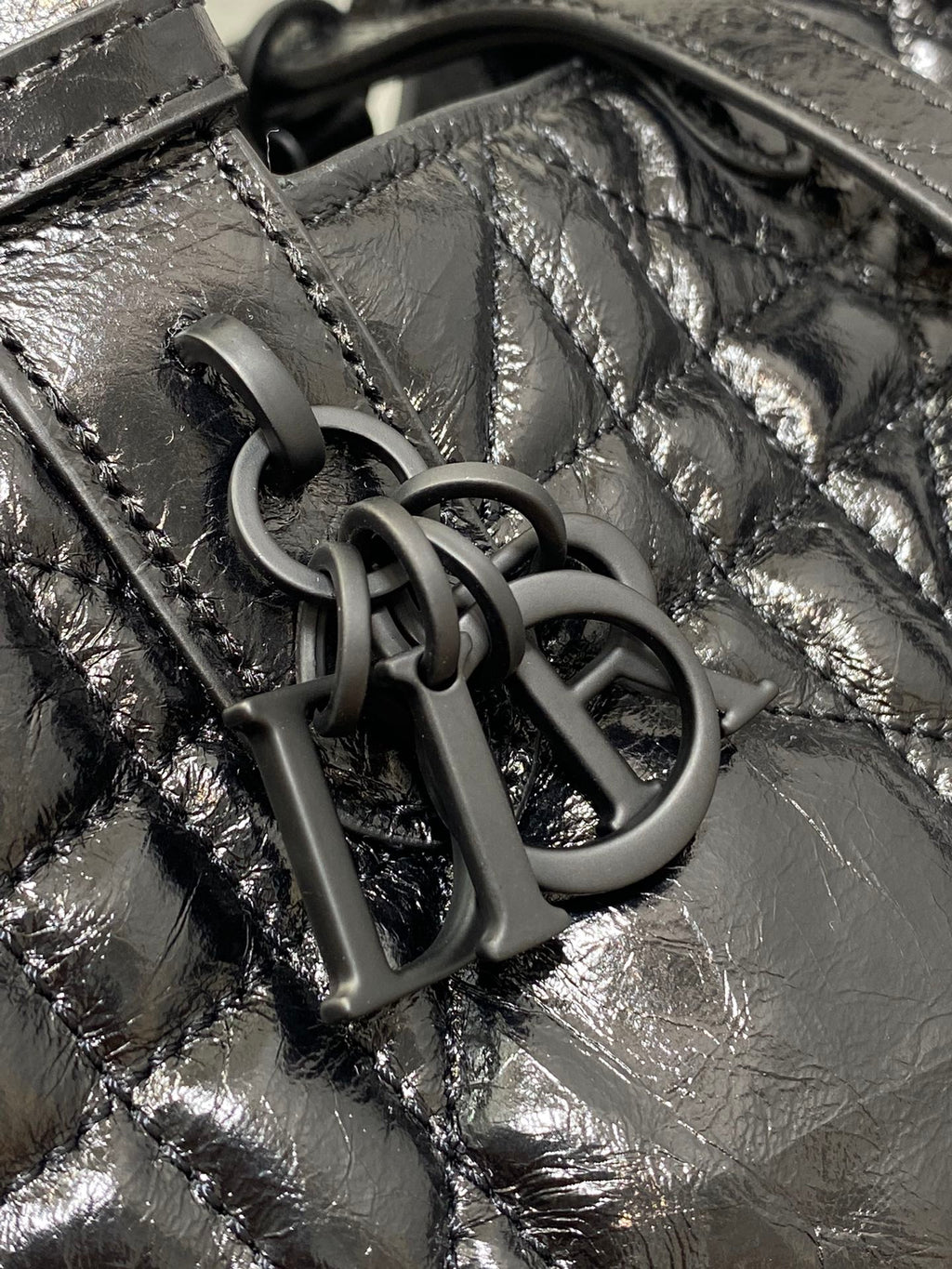 Dior bag hardware close-up: interlocking dark metal 'D I O R' charm on leather
