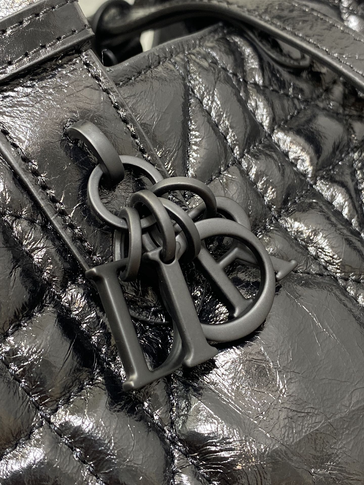 Dior bag hardware close-up: interlocking dark metal 'D I O R' charm on leather