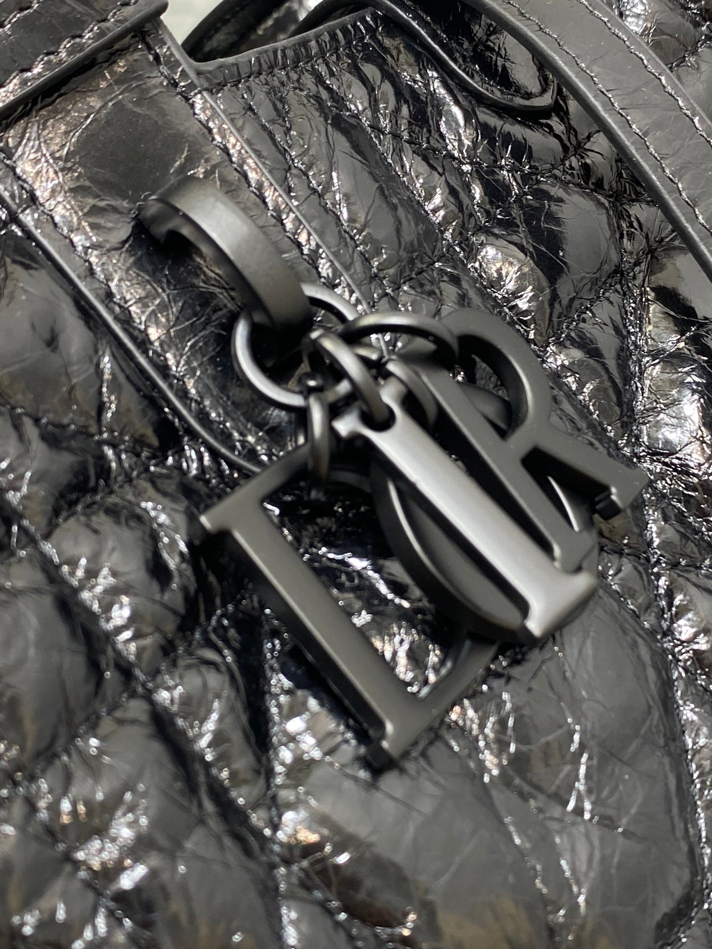 Dior tote bag corner close-up with black hardware and textured metallic leather