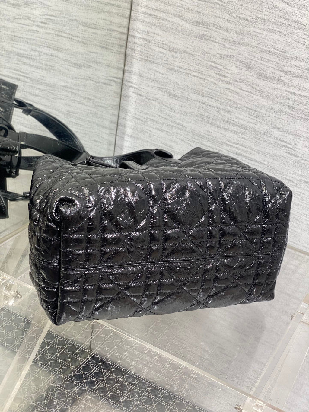 Dior quilted top-handle bag with long strap, curved profile, black glossy leather