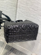 Dior quilted top-handle bag with long strap, curved profile, black glossy leather