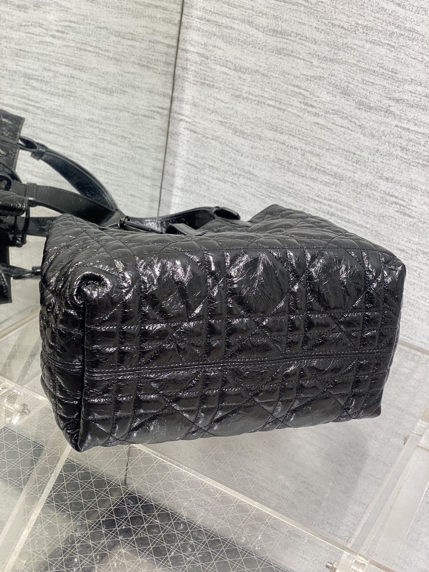 Dior quilted top-handle bag with long strap, curved profile, black glossy leather