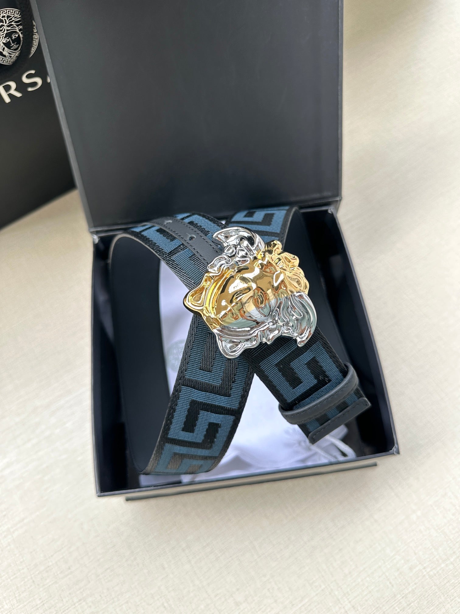 Versace belt in box: blue Greek-key strap with gold/silver Medusa head buckle.