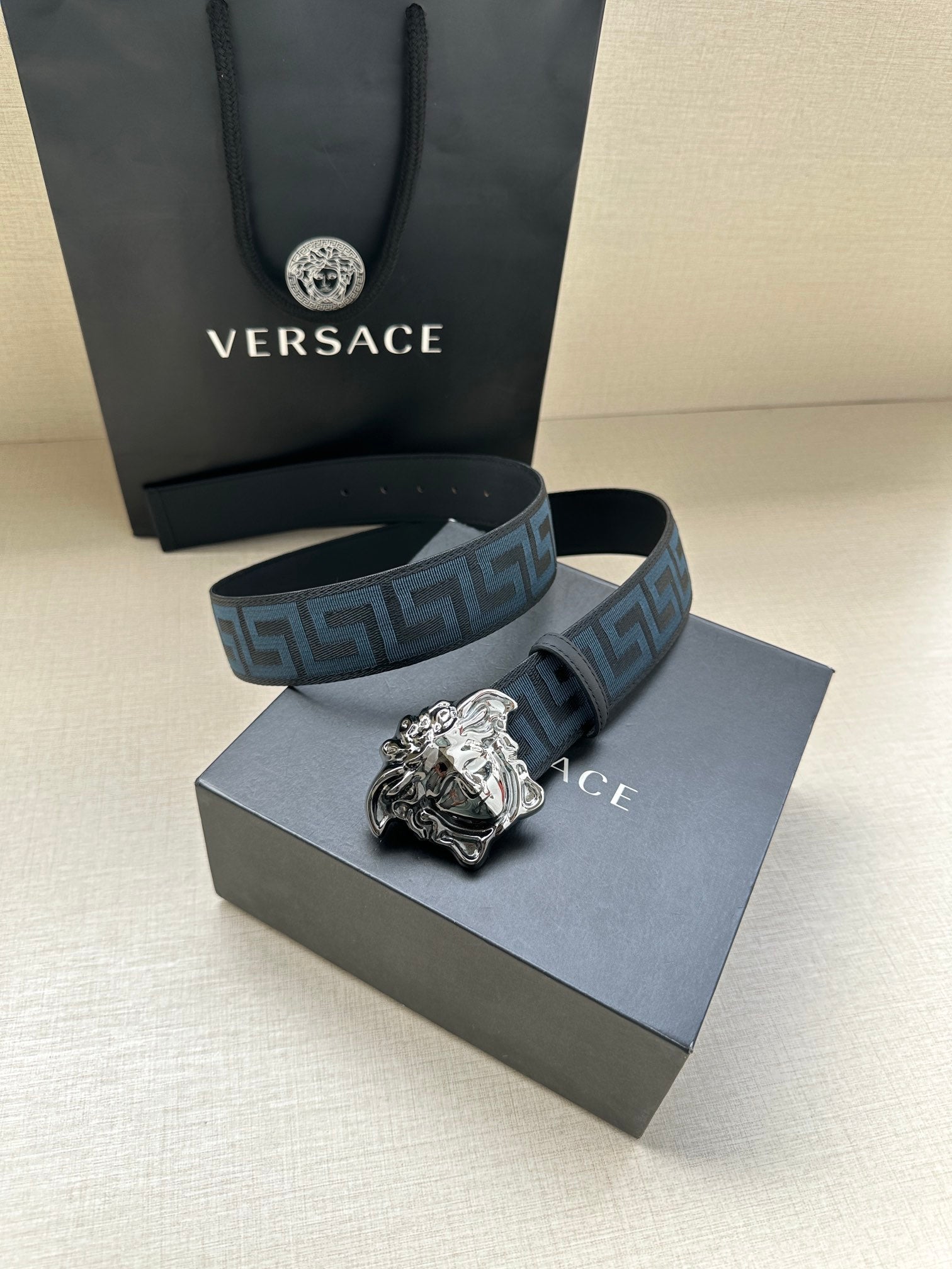 Versace belt with blue geometric pattern strap and silver Medusa buckle, shown with box.