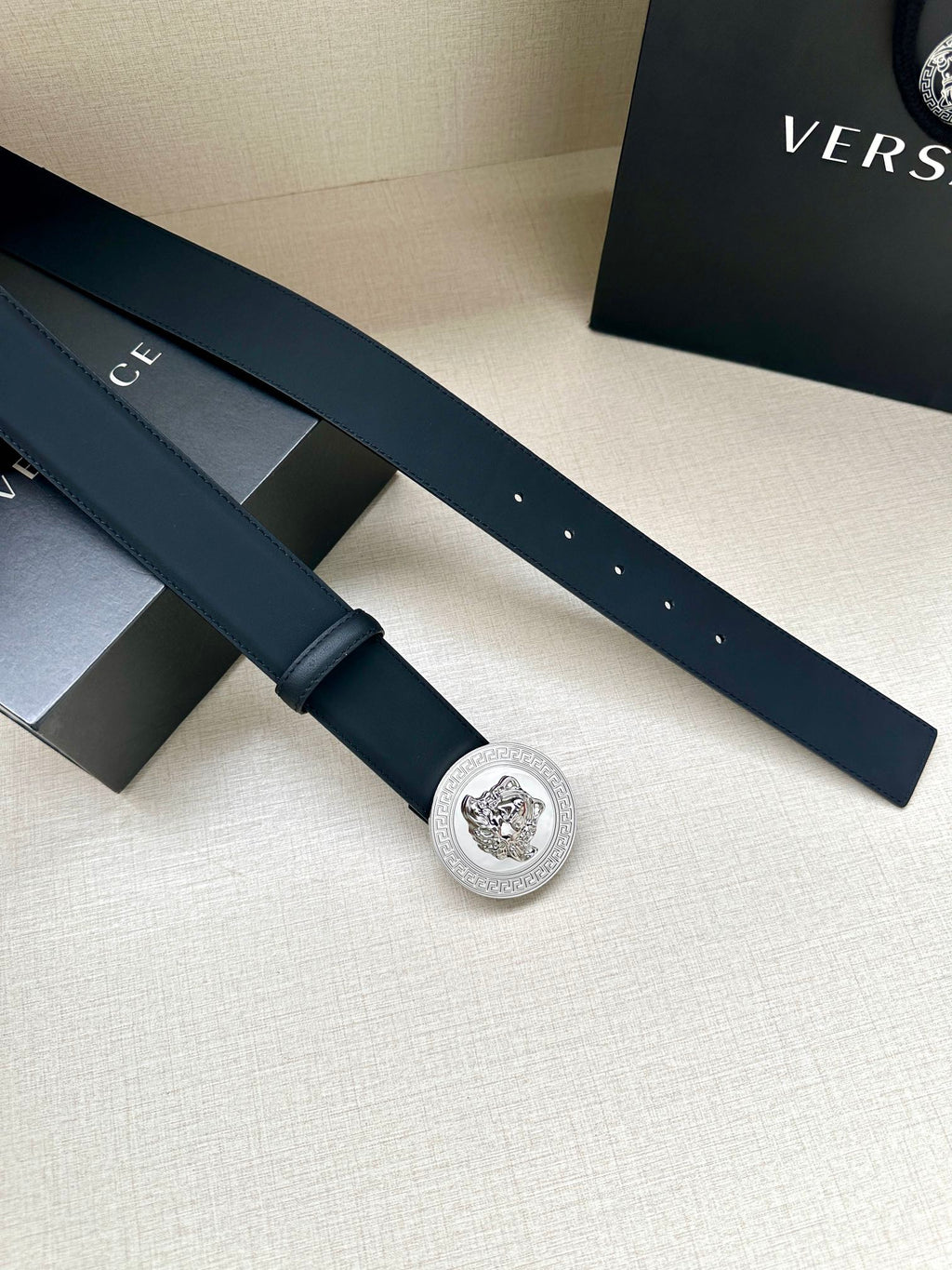 Navy leather belt with round silver medallion buckle, flat laid-out strap