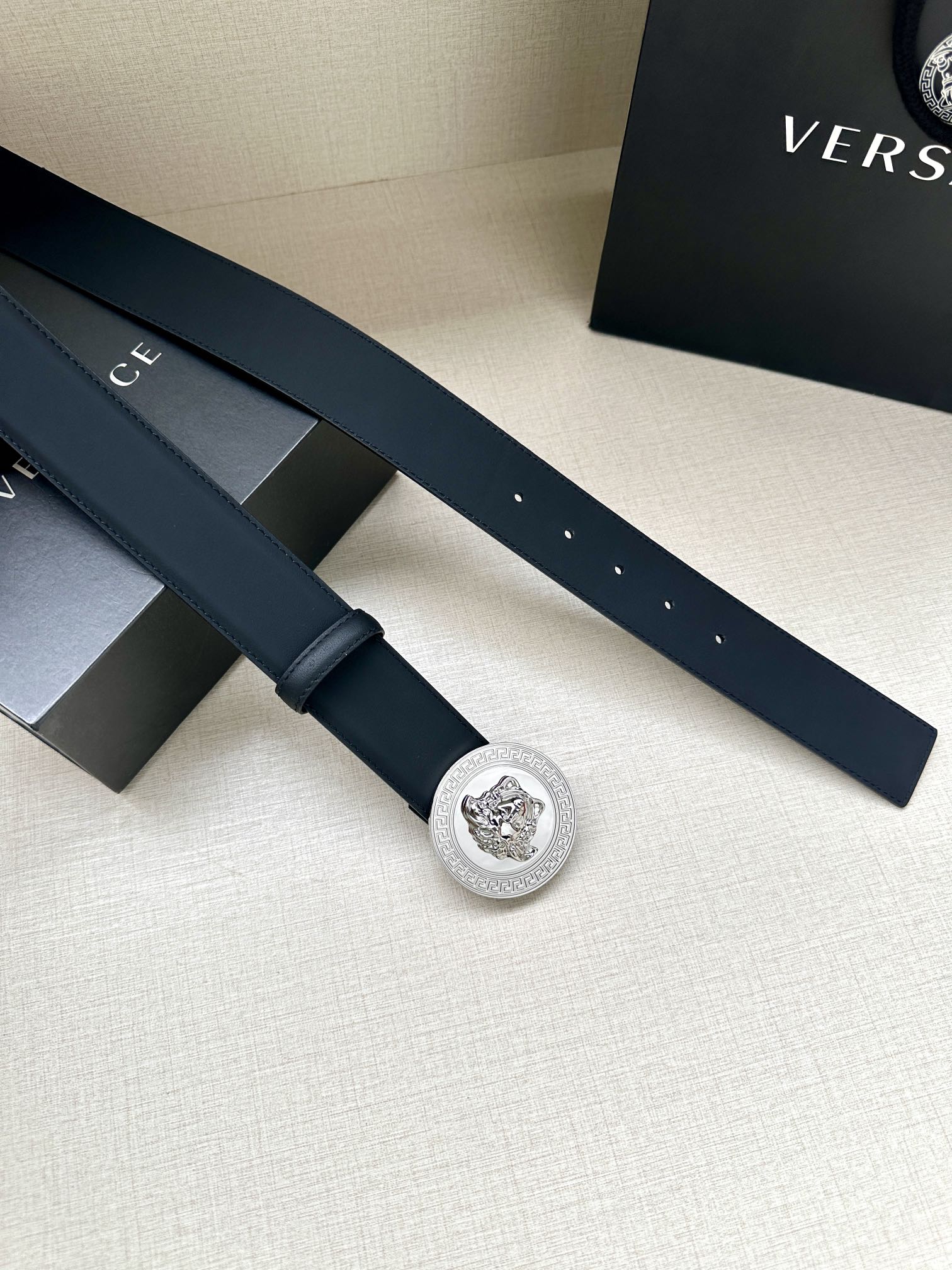 Navy leather belt with round silver medallion buckle, flat laid-out strap