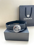 Navy leather belt with round silver medallion buckle, shown on box