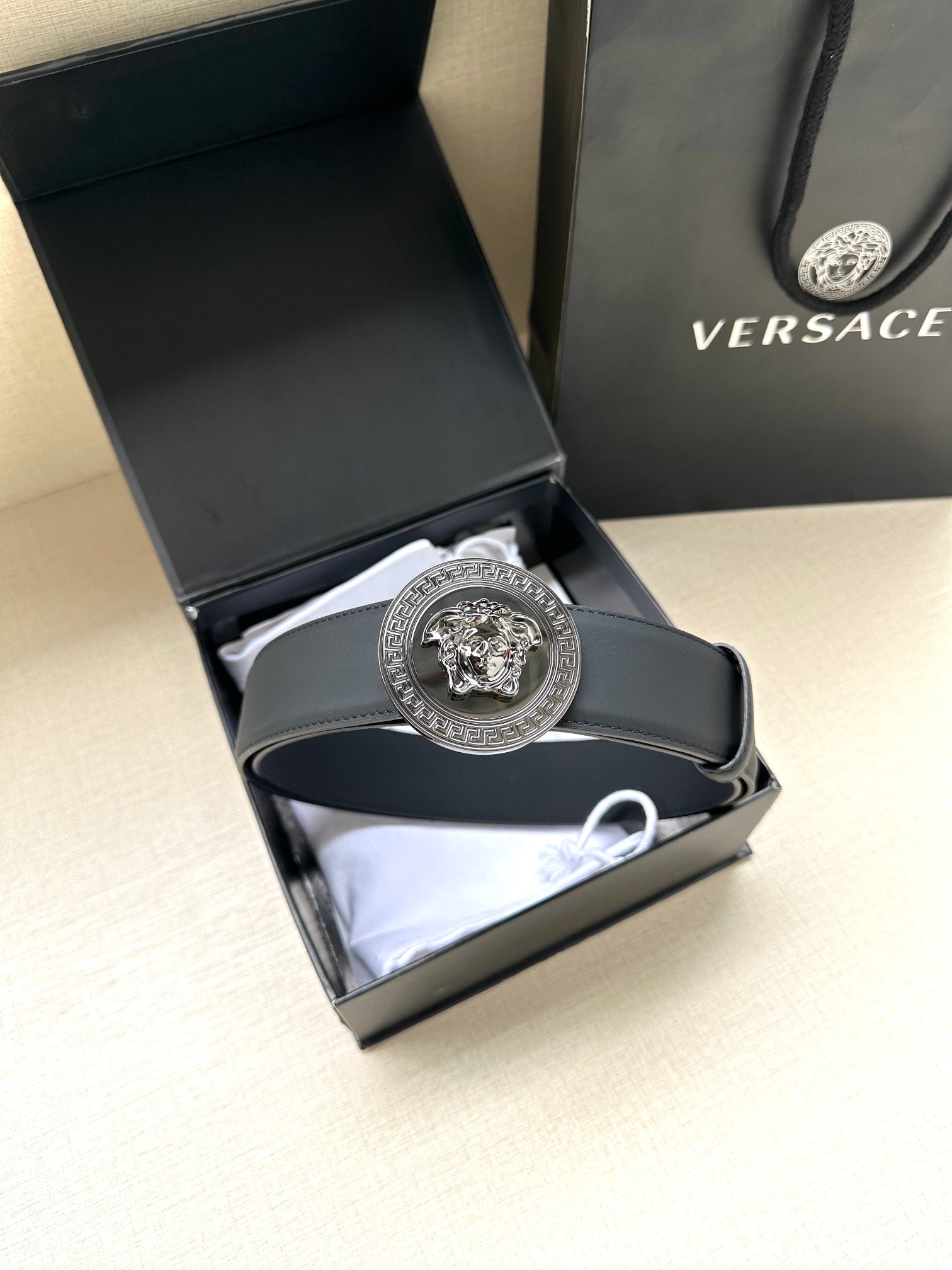 Navy leather belt with round silver medallion buckle in open box tray