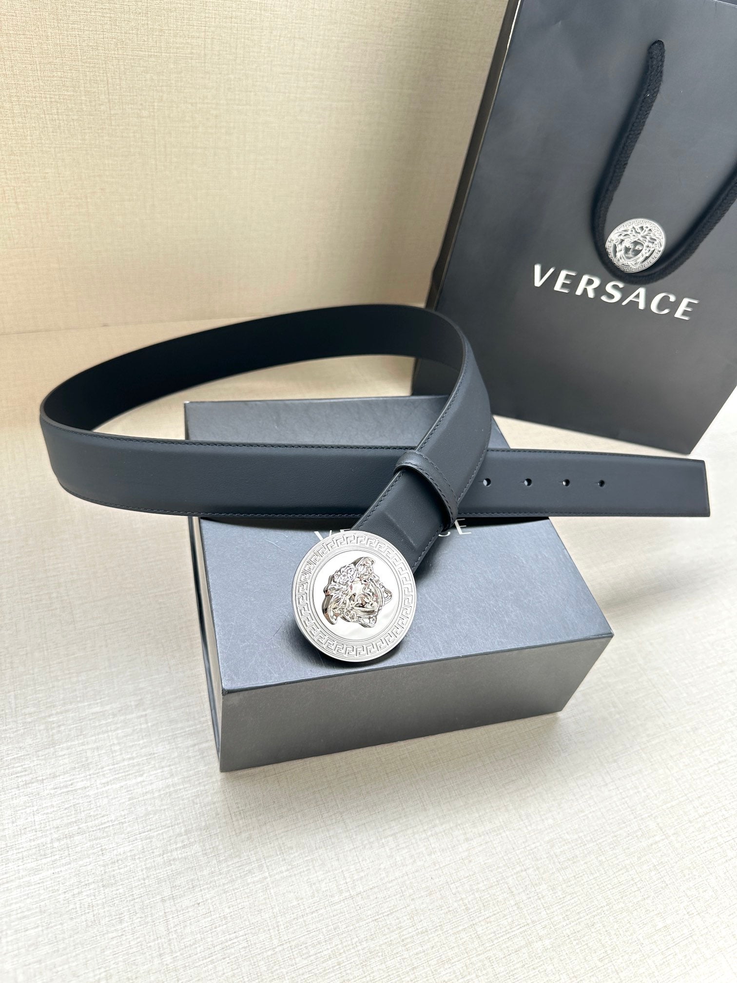 Navy leather belt with round silver medallion buckle, styled on box