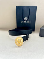 Versace belt in dark blue with gold Medusa medallion buckle, laid across boxes.