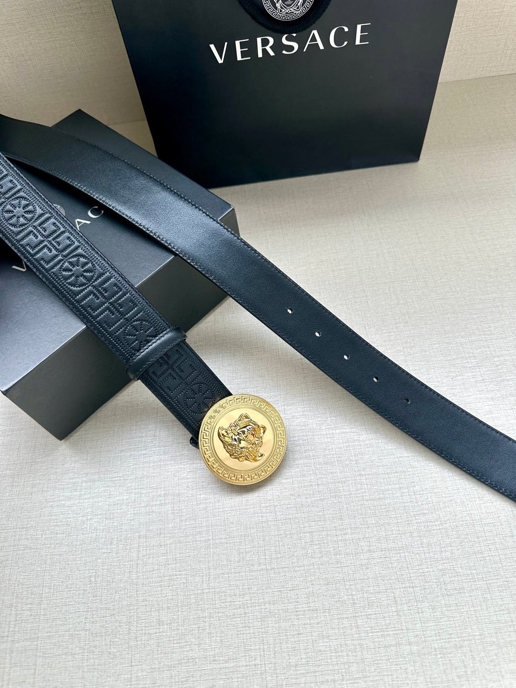 Versace belt in dark blue with gold Medusa medallion buckle on overlapping straps.
