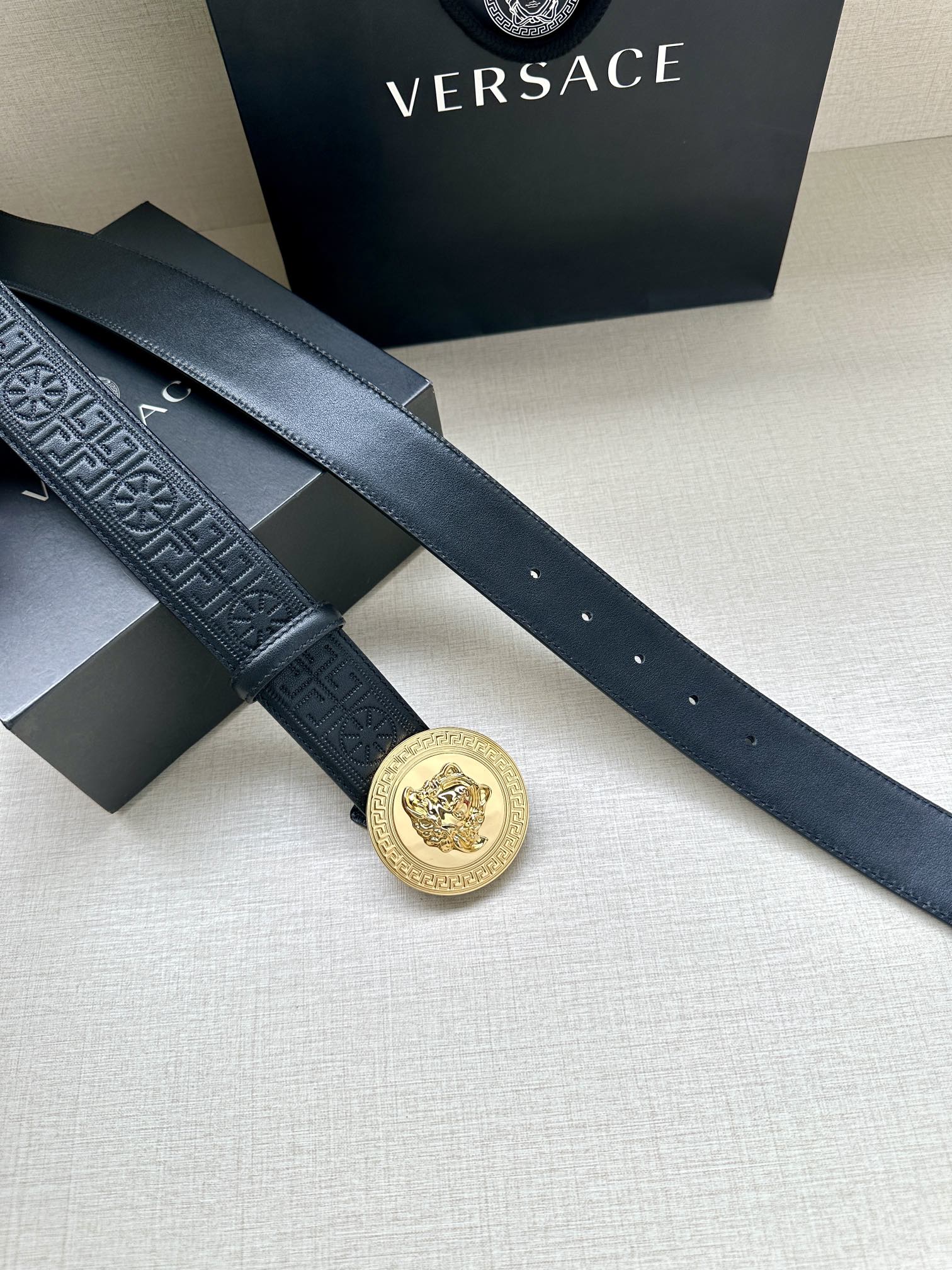 Versace belt in dark blue with gold Medusa medallion buckle on overlapping straps.