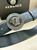 Versace belt close-up: dark blue textured strap with silver Medusa medallion buckle.