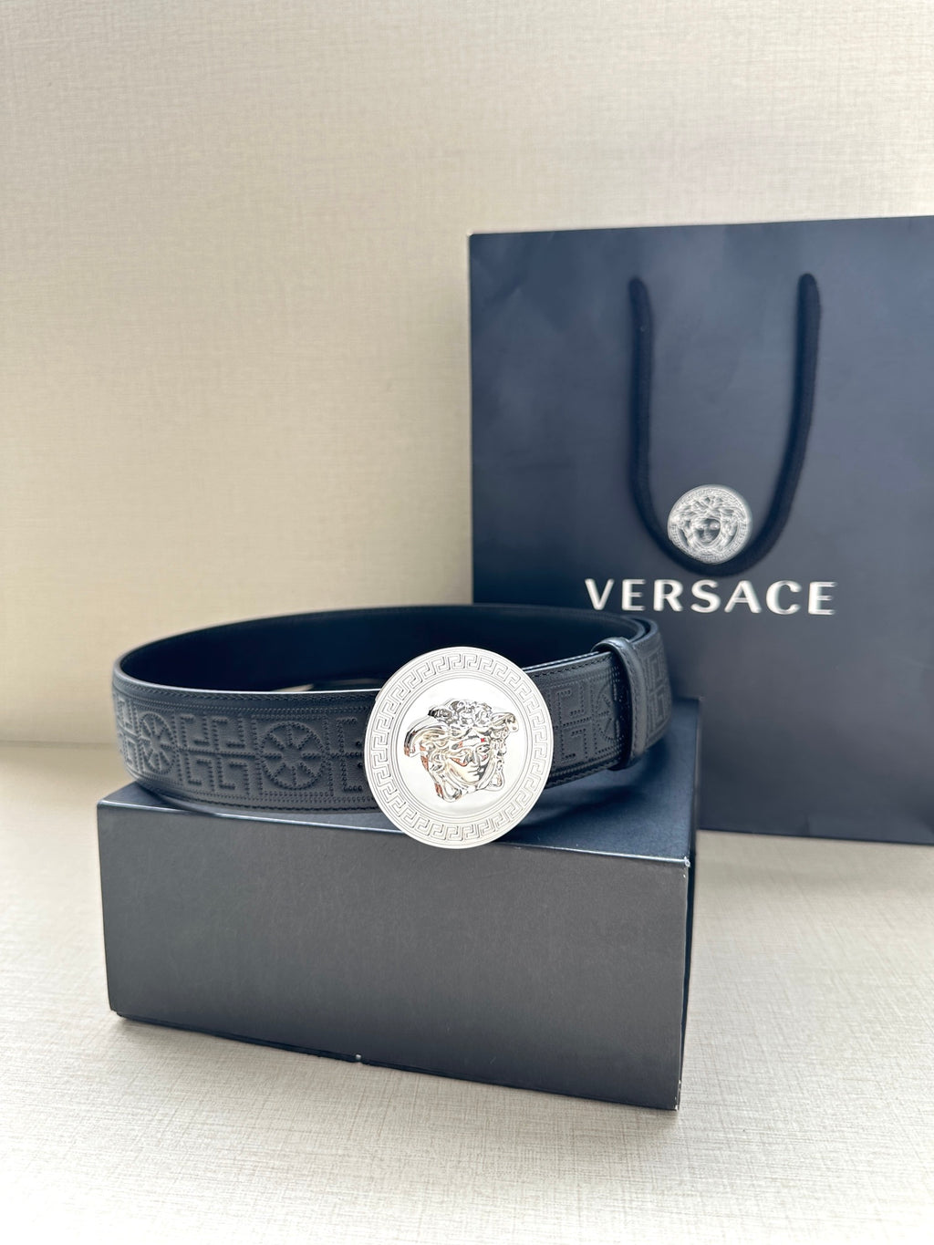 Versace belt in dark blue leather with silver Medusa medallion buckle at center.