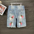 Light blue denim shorts, full front view, with colorful cross patches and frayed edges