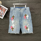Light blue denim shorts with multicolor cross patches and frayed hem