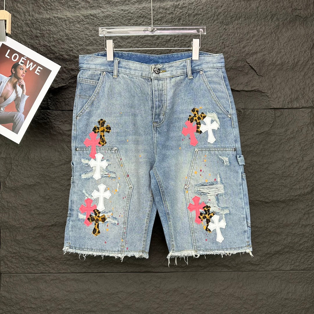 Light blue denim shorts with multicolor cross patches and frayed hem