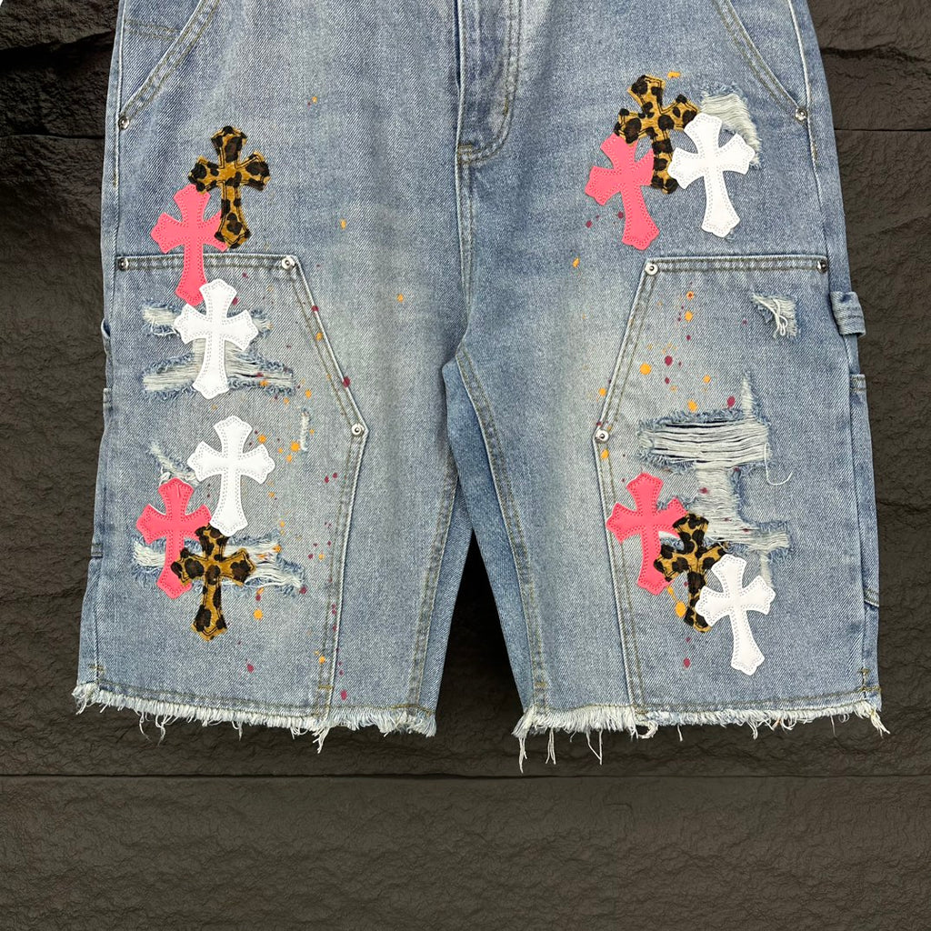Light blue denim shorts with multicolor cross patches and chest-style pins