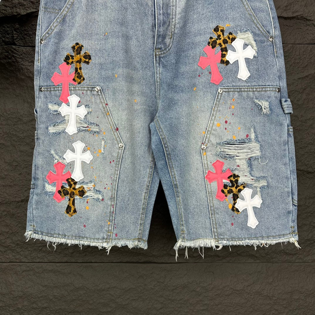 Light blue denim shorts with multicolor cross patches and chest-style pins