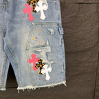Light blue denim shorts front with cross appliqués and distressed pocket details