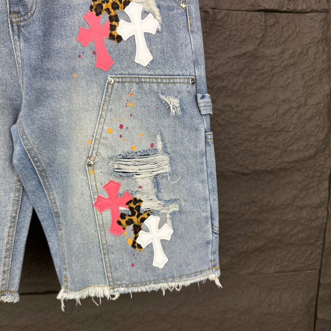 Light blue denim shorts front with cross appliqués and distressed pocket details
