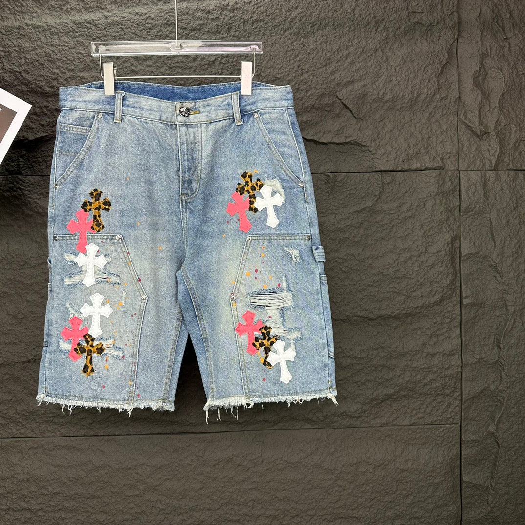 Light blue denim shorts with frayed hem and multicolor cross appliqués