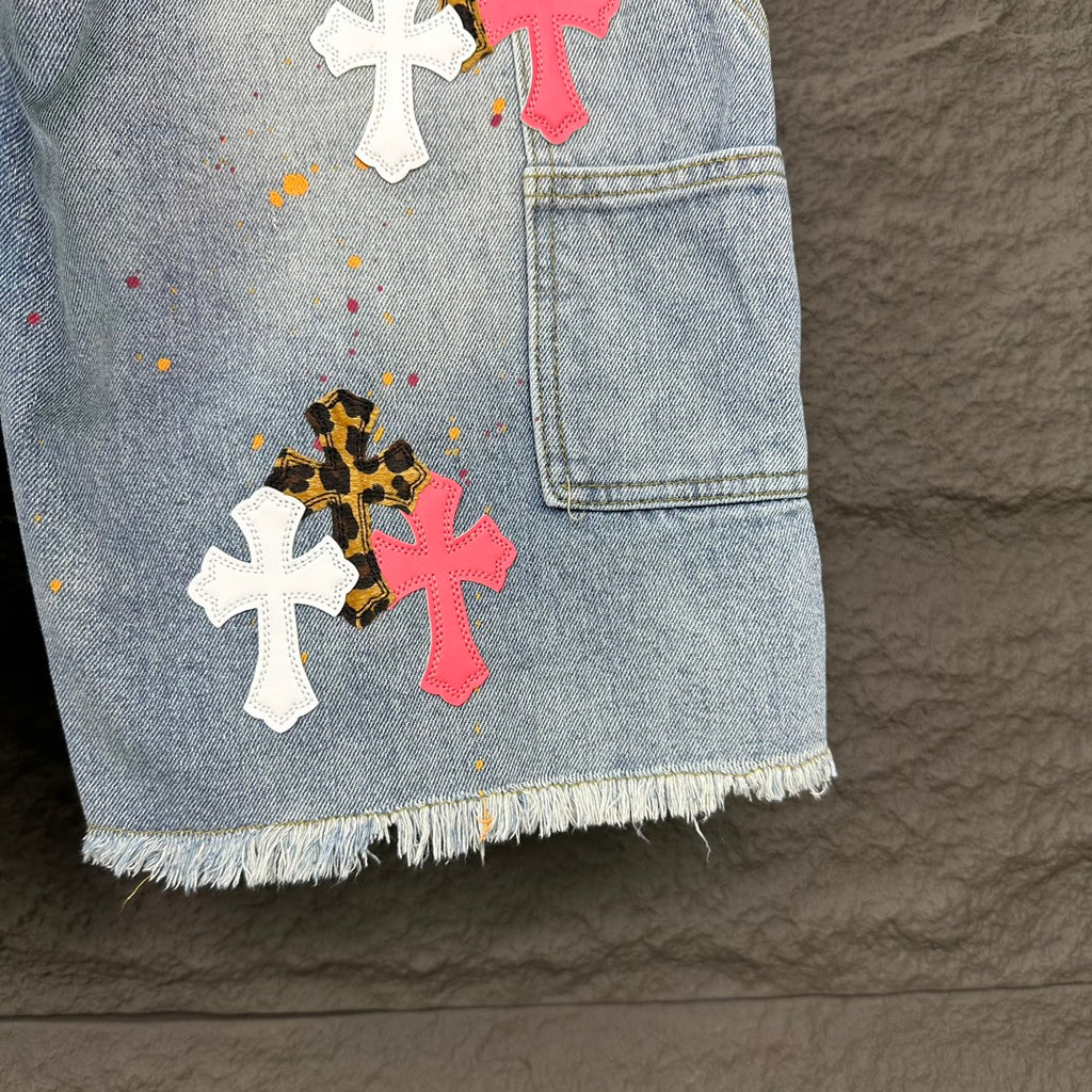 Light blue denim shorts pocket with cross patches in white, pink, and black