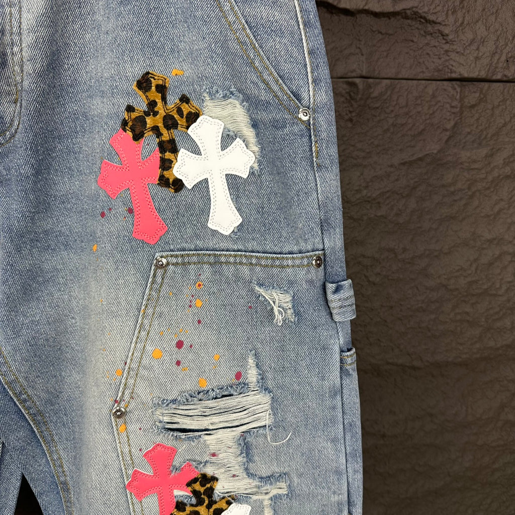 Light blue denim shorts close-up of pocket with cross appliqués and distressing