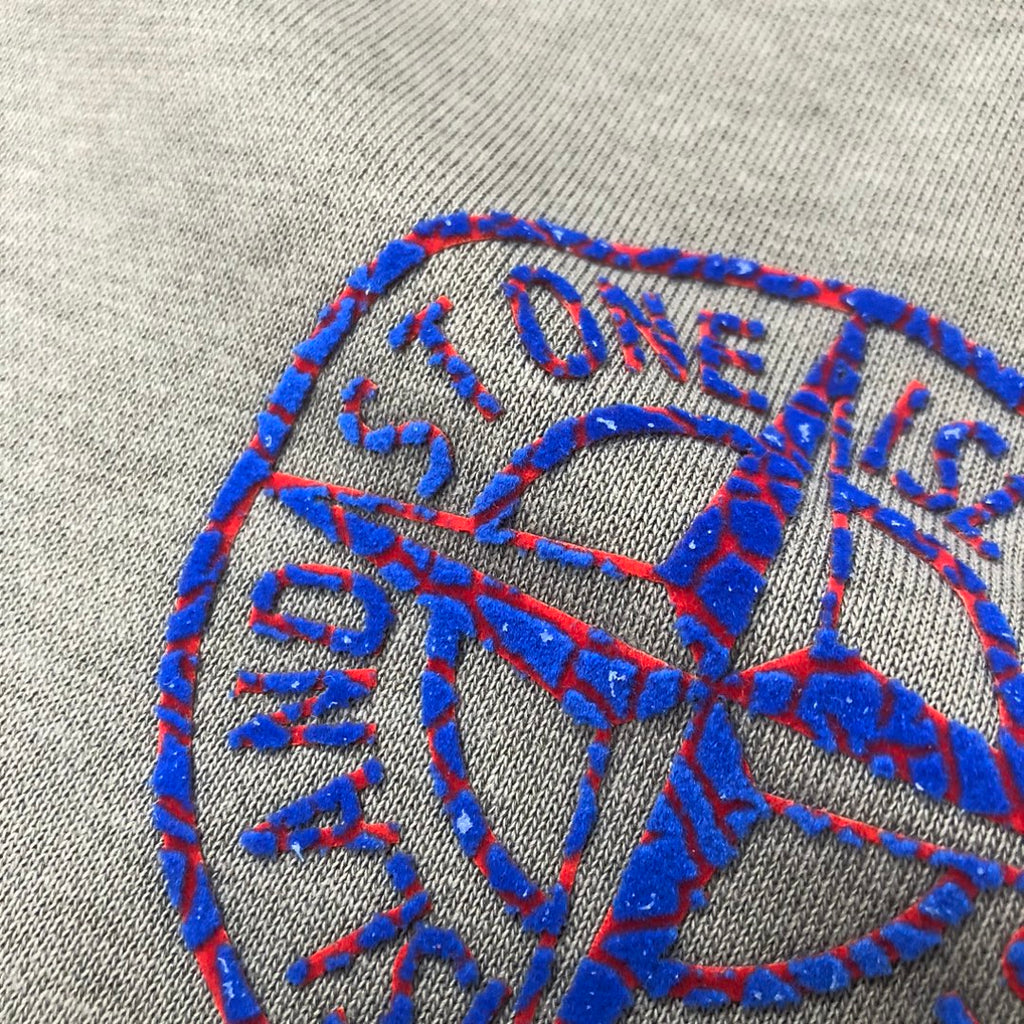 Embroidered blue Stone Island logo graphic on heather gray fabric