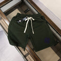 Stone Island green drawstring shorts with blue circular logo, white ties