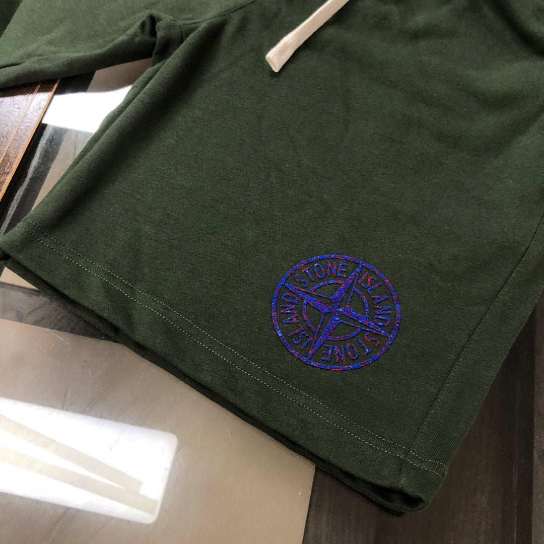 Dark green shorts hem with blue circular logo patch and stitched edge