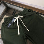 Dark green drawstring shorts with white ties and blue circular emblem