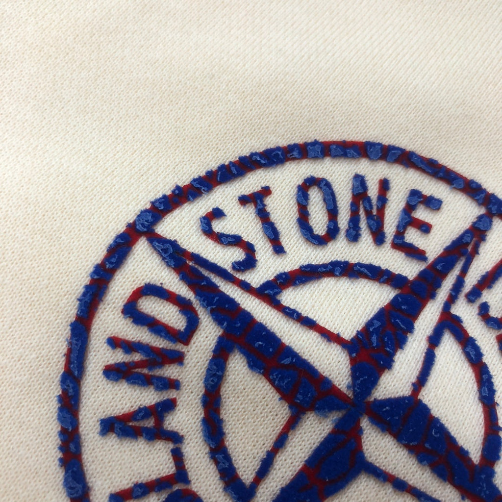 Stone Island blue embroidered circular logo on light cream fabric