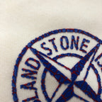 Stone Island blue embroidered circular logo on light cream fabric