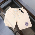 Stone Island logo drawstring shorts, light cream with blue patch on the leg