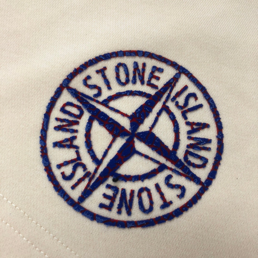 Stone Island circular logo patch in blue embroidery on light cream fabric