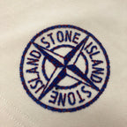 Stone Island circular logo patch in blue embroidery on light cream fabric