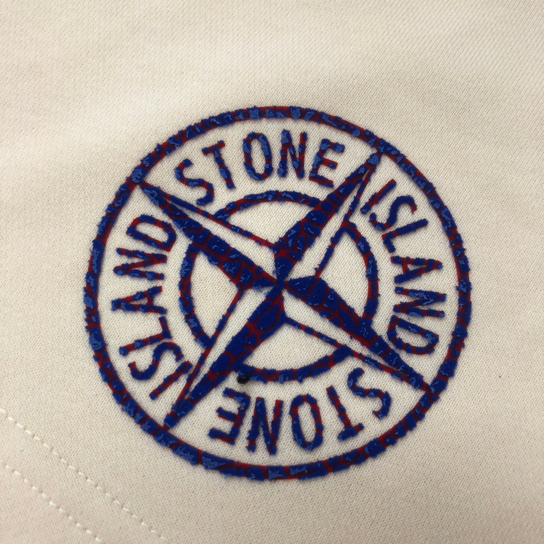 Stone Island circular logo patch in blue embroidery on light cream fabric