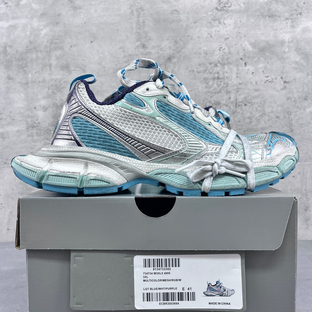 Balenciaga running shoes side view with blue mesh panels and white lace-up uppers.