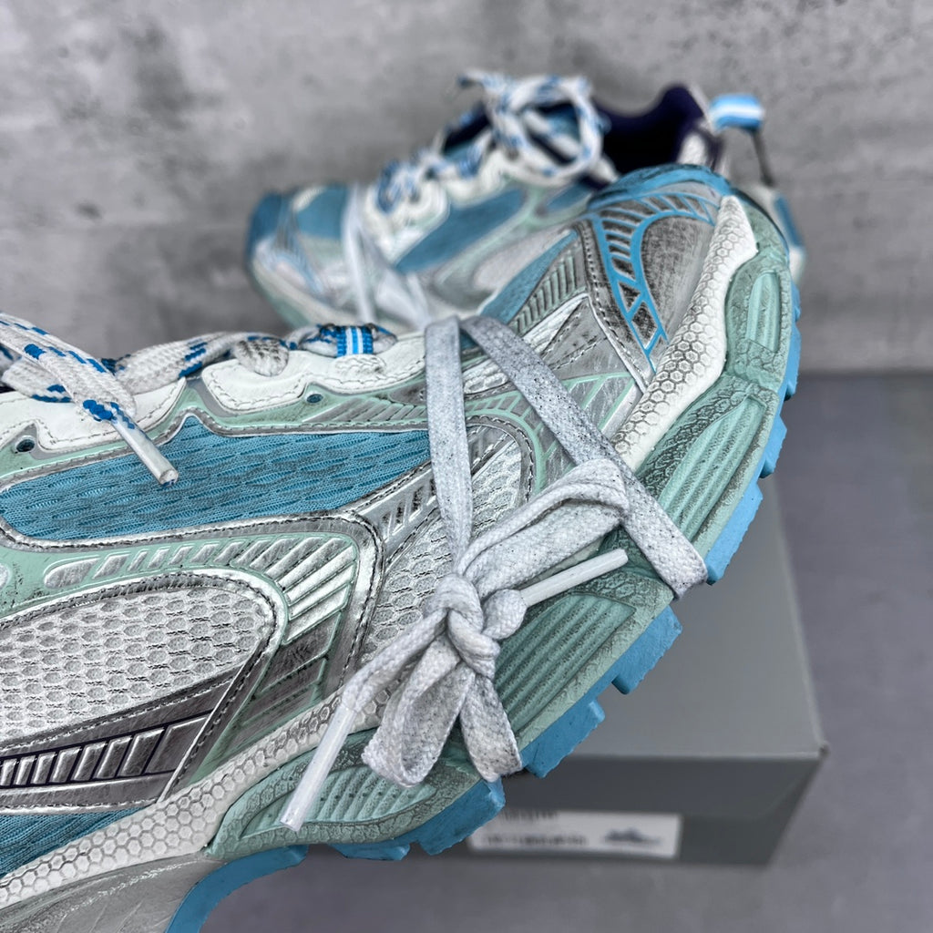 Balenciaga running shoes close-up with aqua and silver textures and white laces.