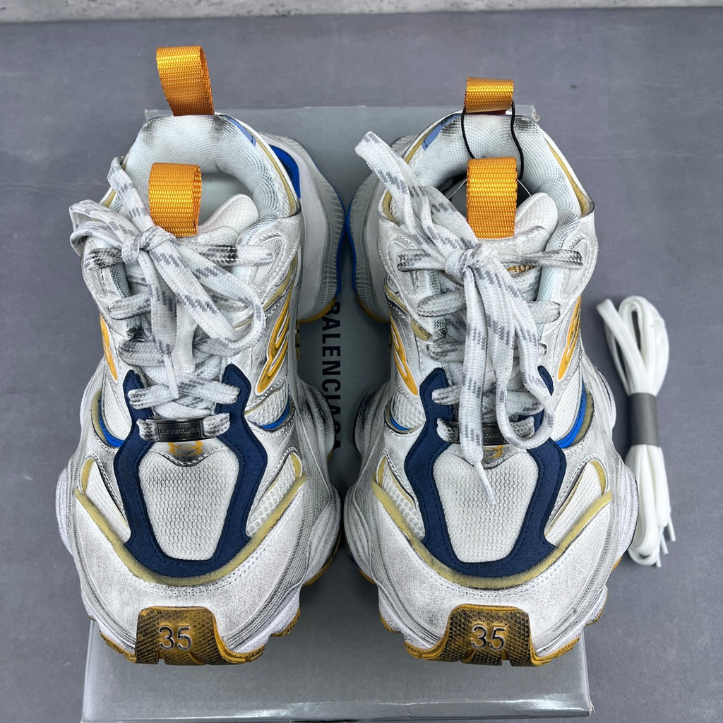 Balenciaga unisex sneakers with yellow pull tabs, white laces, and blue-and-gold heel branding.