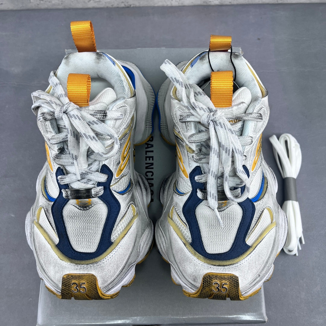 Balenciaga unisex sneakers with yellow pull tabs, white laces, and blue-and-gold heel branding.
