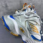 Balenciaga unisex sneaker front view with lace-up closure, blue side panel, and gold logo.