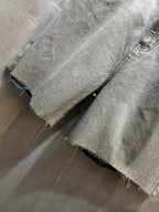 Balenciaga denim shorts close-up with frayed hem and distressed wash