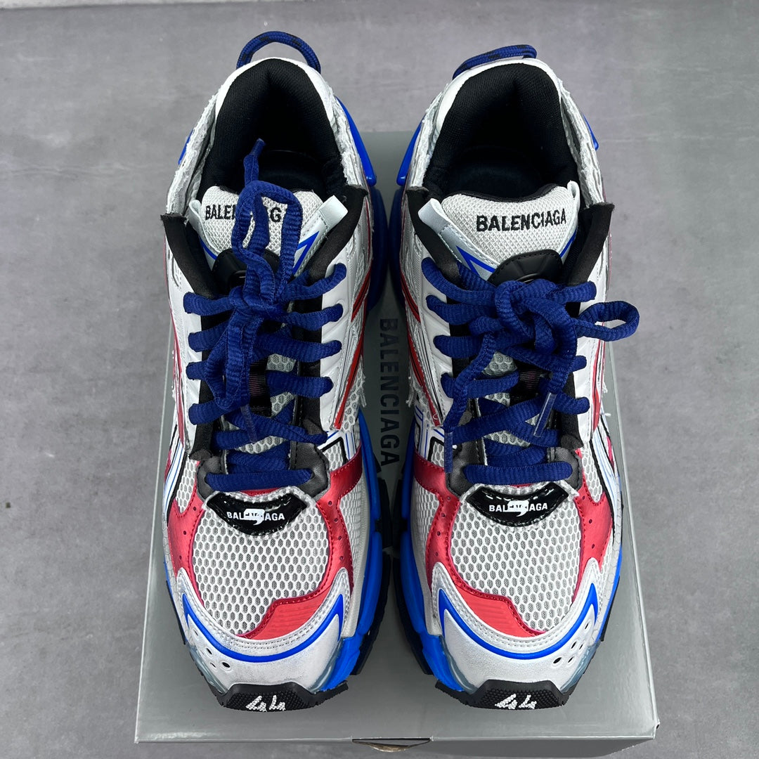 Pair of lace-up chunky sneakers with white uppers, red inserts, and blue laces.
