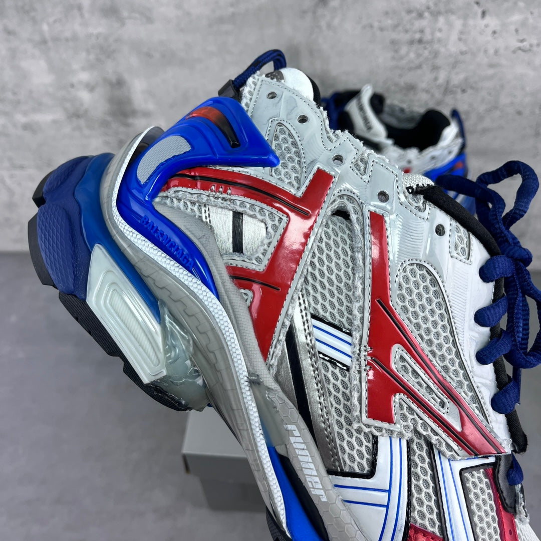 Side view of white and blue chunky sneakers with red stripes and thick sole.